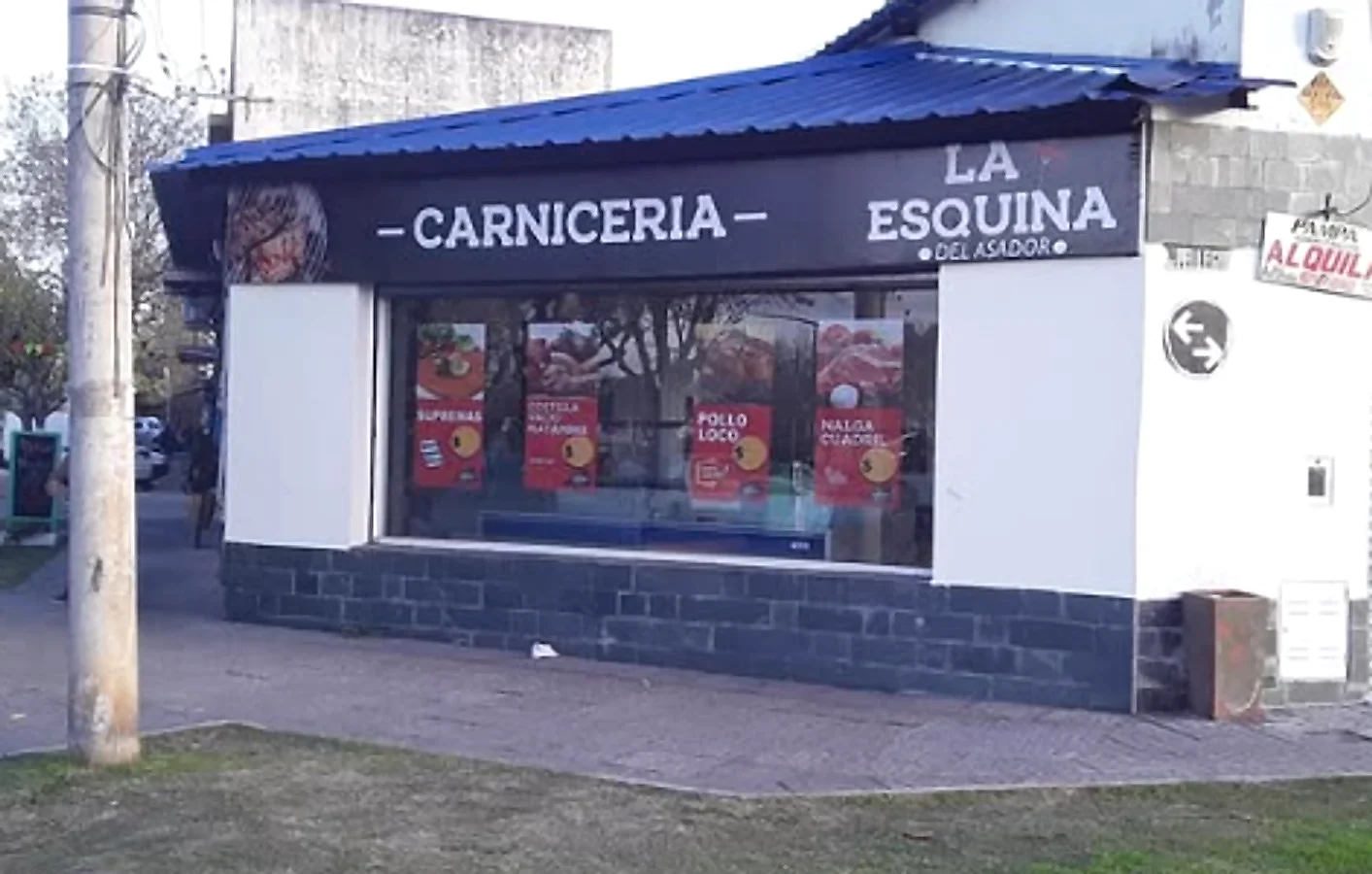 Cartel de fachada de la carnicería La Esquina del Asador y gráfica en vidriera