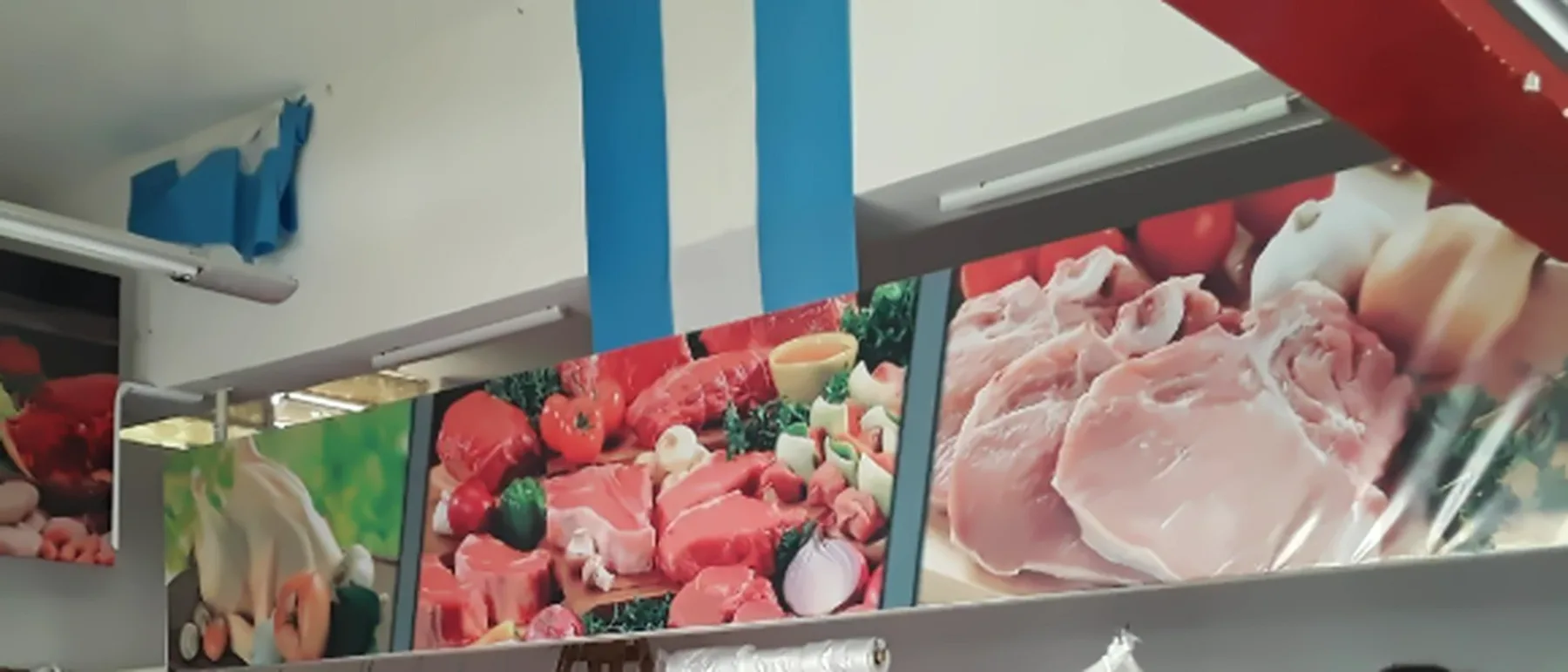 Paneles impresos con fotos de cortes de carne y verduras sobre el mostrador de Provincias Unidas